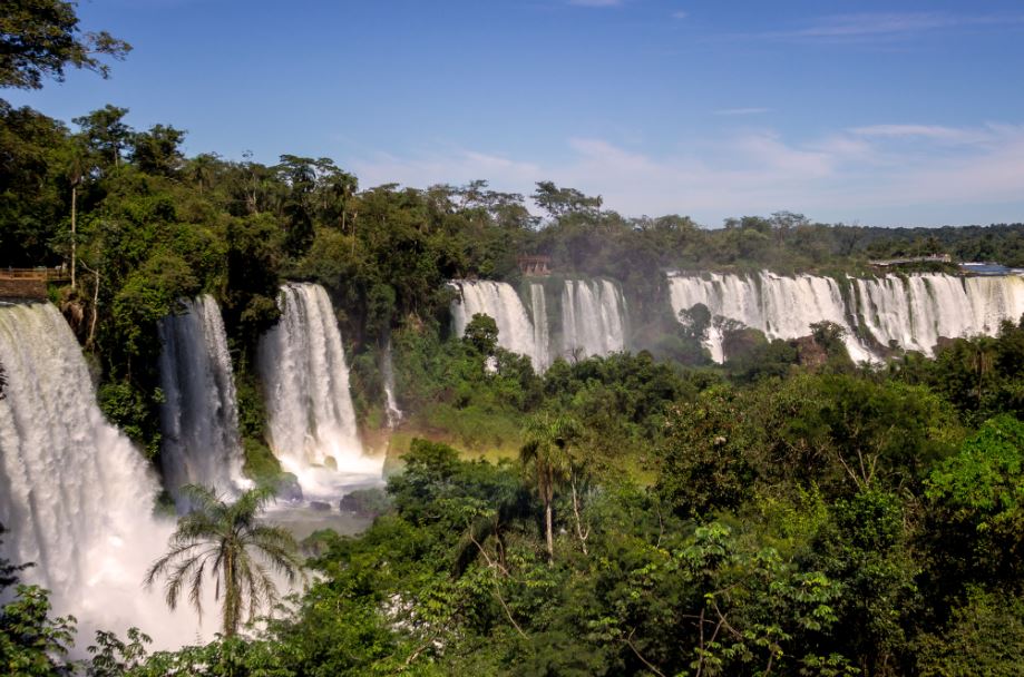Pela sua beleza natural exuberante, Foz do Iguaçu é um dos destinos mais visitados no Brasil. É uma cidade que tem tudo para cativar o coração dos turistas, oferecendo paisagens naturais de tirar o fôlego. Se você quer saber o que fazer em Foz do Iguaçu, leia esse guia. O que fazer em Foz do Iguaçu: qual o melhor período para viajar? Apesar de estar localizada na região Sul do país, a cidade costuma ter verões com altas temperaturas, o que é ótimo, já que a maioria dos passeios em Foz do Iguaçu são realizados na água. Porém, também é possível aproveitar o município no inverno, que é muito rigoroso nos meses de julho e agosto. Nessa época, os pontos turísticos Foz Iguaçu se tornam os festivais de buffets de sopas, fondues e cafés coloniais. Turismo em Foz do Iguaçu: conheça os pontos mais famosos Aconchegante, o turismo em Foz do Iguaçu tem tudo para cativar o coração de qualquer pessoa. São tantos pontos turísticos que os turistas precisam dividir a sua atenção entre as paisagens naturais inesquecíveis, espécies raras de animais e muito verde, além das Cataratas, que estão entre as principais atrações da cidade. O município também conta com atividades radicais, parques, hotéis sofisticados e restaurantes, trazendo diversão para todos os gostos. Conheça algumas dicas para quem quer saber o que tem para fazer em Foz do Iguaçu: Parque Nacional do Iguaçu Esse ponto turístico em Foz do Iguaçu faz fronteira com a Argentina e é representado por 185 mil hectares no território brasileiro. Conhecido por ser considerado Patrimônio Natural da Humanidade pela Unesco, o parque abriga atrações como trilhas e atividades de ecoaventura, como rafting, rapel, escalada em rocha e passeios em barcos. Cataratas do Iguaçu Esse é o ponto turístico mais famoso de Foz do Iguaçu. As cataratas são formadas pelo Rio Iguaçu que, antes de se juntar com o Rio Paraná, passa por um desnível de 275 quedas de 65 metros de altura, na fronteira com a Argentina. No local, há uma trilha que passa por vários mirantes e um elevador panorâmico ligando a base das quedas ao nível superior do rio. Parque das Aves Criado em 1994, esse parque oferece condições de preservação ambiental e reprodução de animais. São 17 hectares de mata nativa, onde é possível visitar viveiros de aves tropicais raras, como araras, periquitos, tucanos, papagaios e diversas outras espécies. Atualmente, são mais de 1.500 aves de 140 espécies diferentes disponíveis no parque. Macuco Safári Localizado dentro do Parque Nacional do Iguaçu, este local oferece passeios de barco pelas quedas das Cataratas com toda a segurança necessária para que os turistas possam curtir sem se preocupar. Passeio de helicóptero Para quem quer curtir algo diferente, é possível também fazer um passeio de helicóptero que sai do Parque Nacional do Iguaçu e sobrevoa toda a cidade, sendo possível ver todas as suas atrações naturais. Vai viajar? Não deixe de contratar um Seguro Viagem! Ao contrário do que muitas pessoas pensam, um Seguro Saúde Viagem é muito mais do que um Seguro com coberturas para problemas de saúde, porque, além das coberturas médicas, esse tipo de apólice possui o objetivo de prestar um suporte completo ao viajante e ajudá-lo com diversos problemas que possam ocorrer durante o seu passeio. Por esse motivo, é sempre recomendável contratá-lo quando for viajar. É uma ótima forma de ter mais tranquilidade ao investir em um fim de semana de descanso ou uma viagem mais prolongada com a família. Leia também: Melhor Seguro Viagem Viagem em família