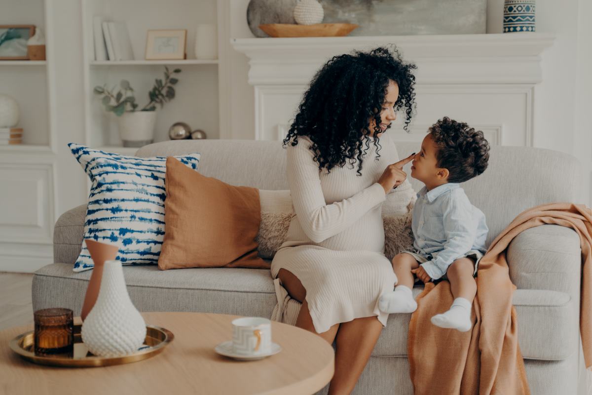 A imagem mostra uma cena doméstica calorosa e afetuosa entre uma mãe e seu filho pequeno.